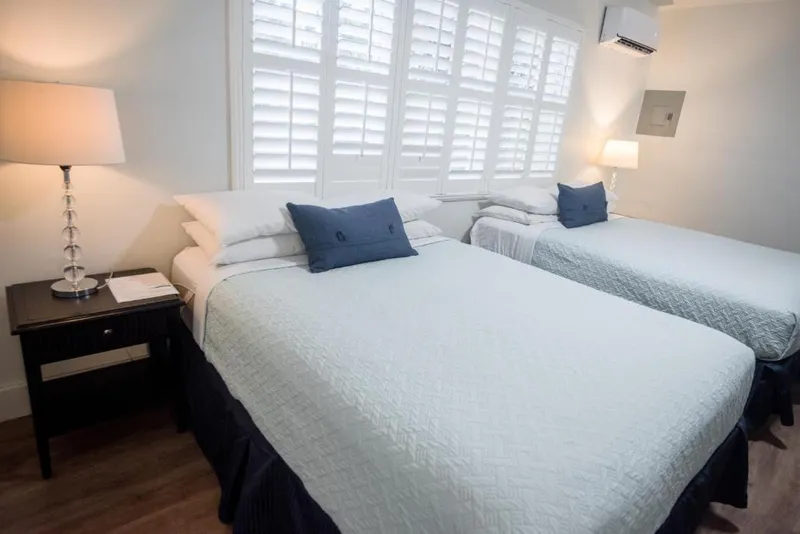 Two queen beds with white quilts and navy pillows